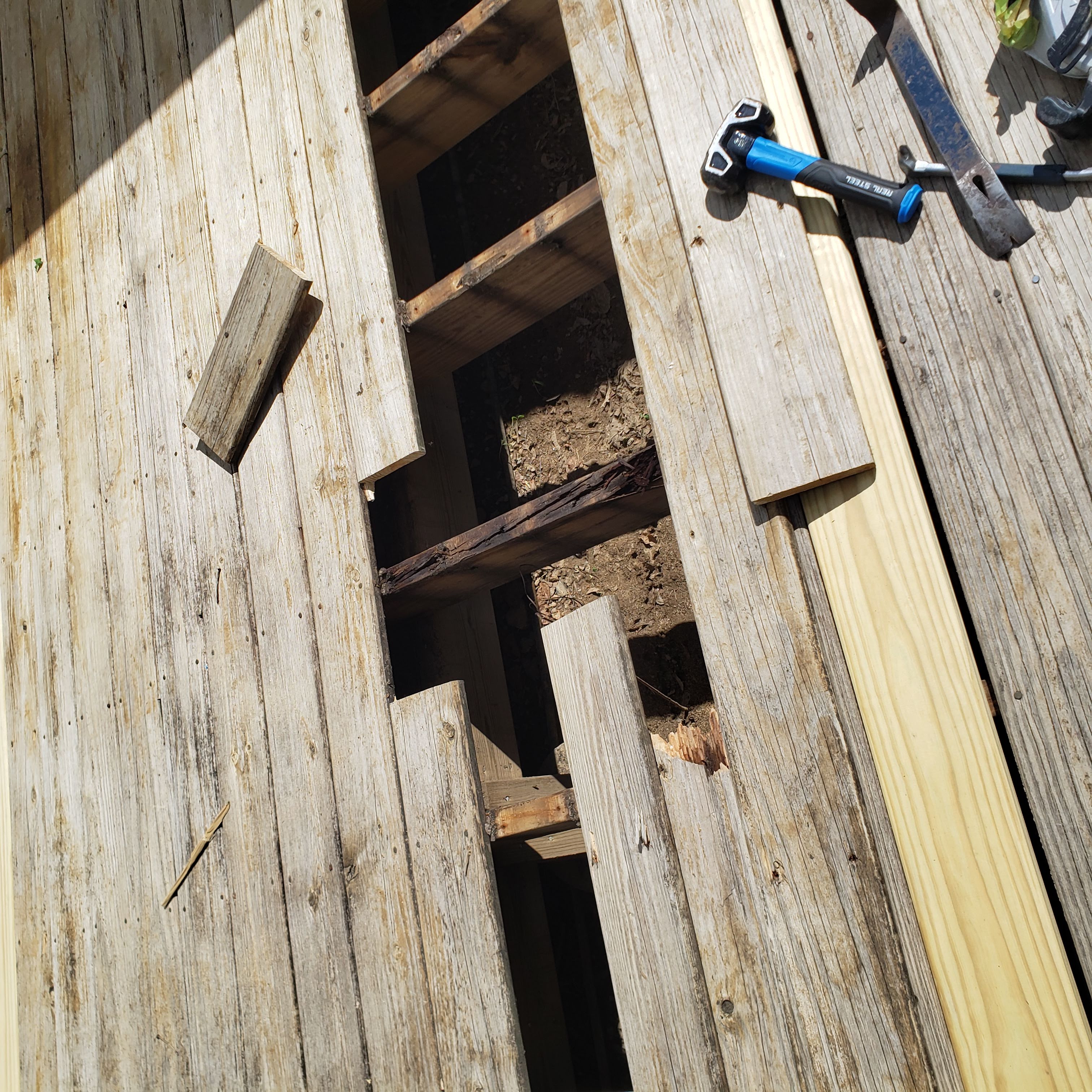 Deck with boards removed to reveal severely rotted joist framing beneath the walking surface
